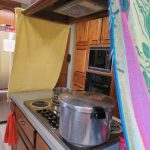 Towels clamped to overhead vent on either end of the stove top island.