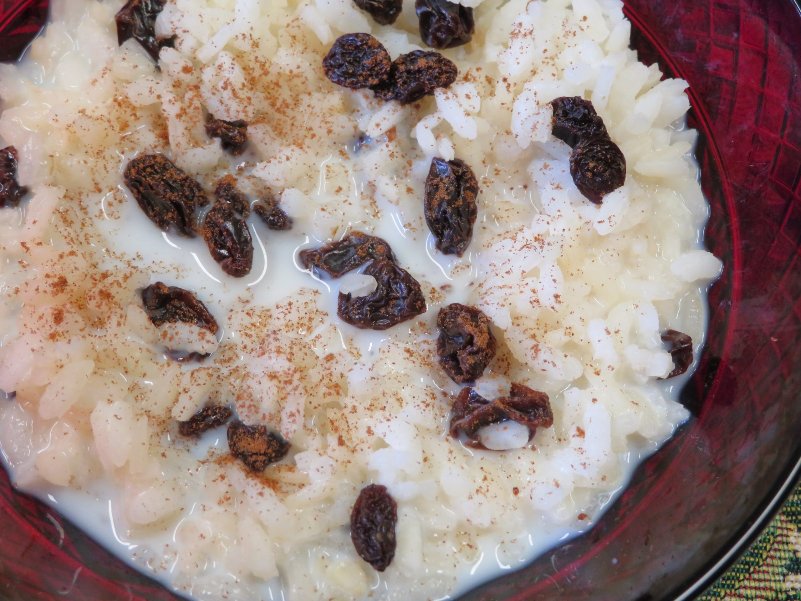 Sweetened rice, raisins, and cinnamon in a red bowl.