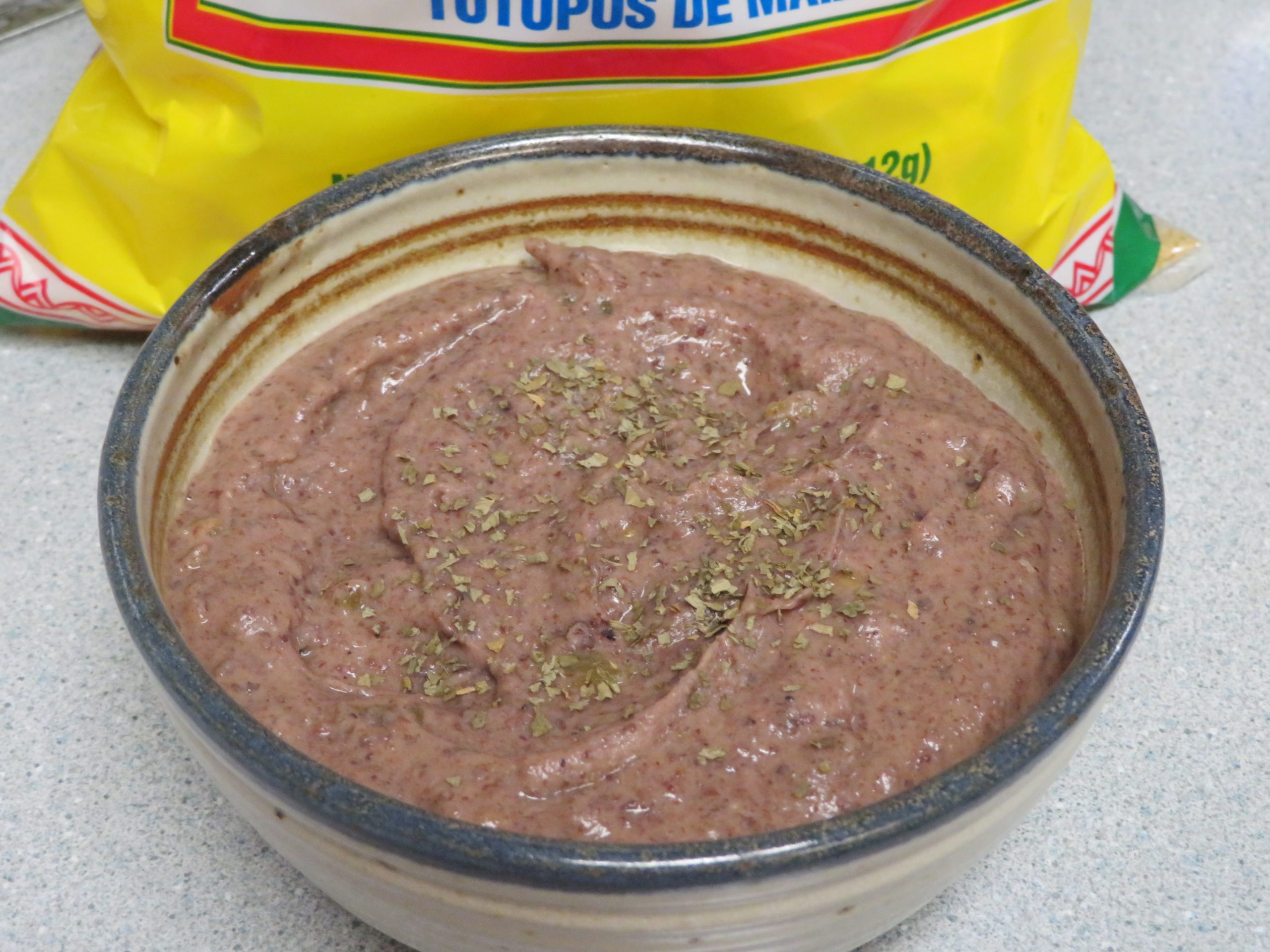 Bowl of Black Bean Dip in front of a bag of tortilla chips