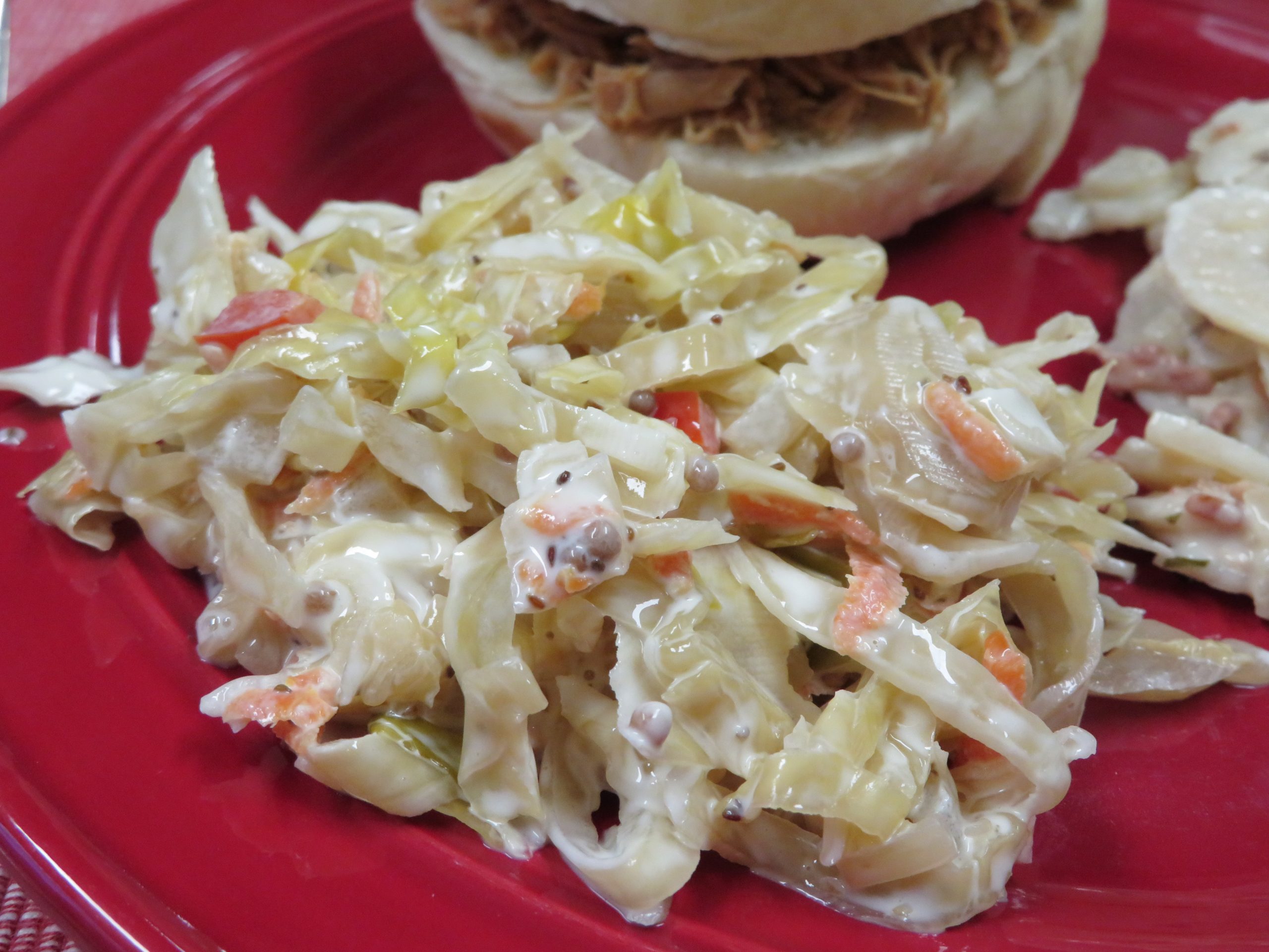 Pickled Cabbage Slaw on a red plate with a BBQ sandwich