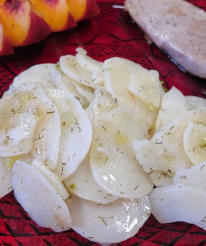 Warm Vinegar and Dill Potato Salad on a red plate