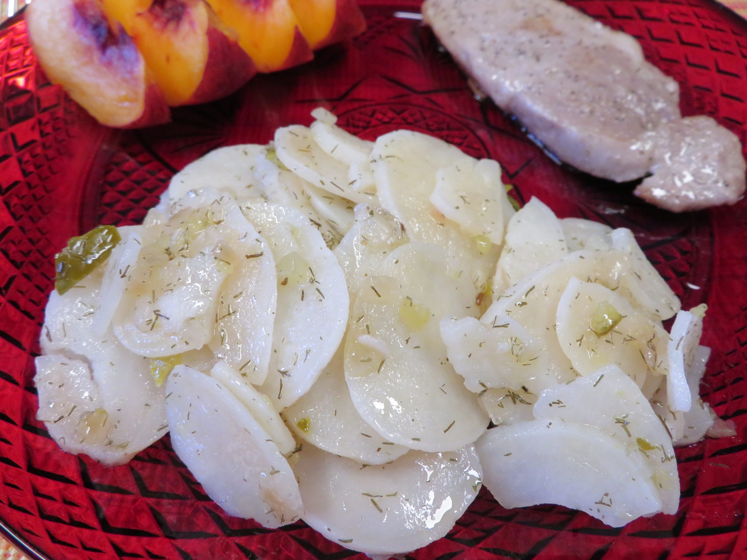 Warm Vinegar and Dill Potato Salad on a red plate