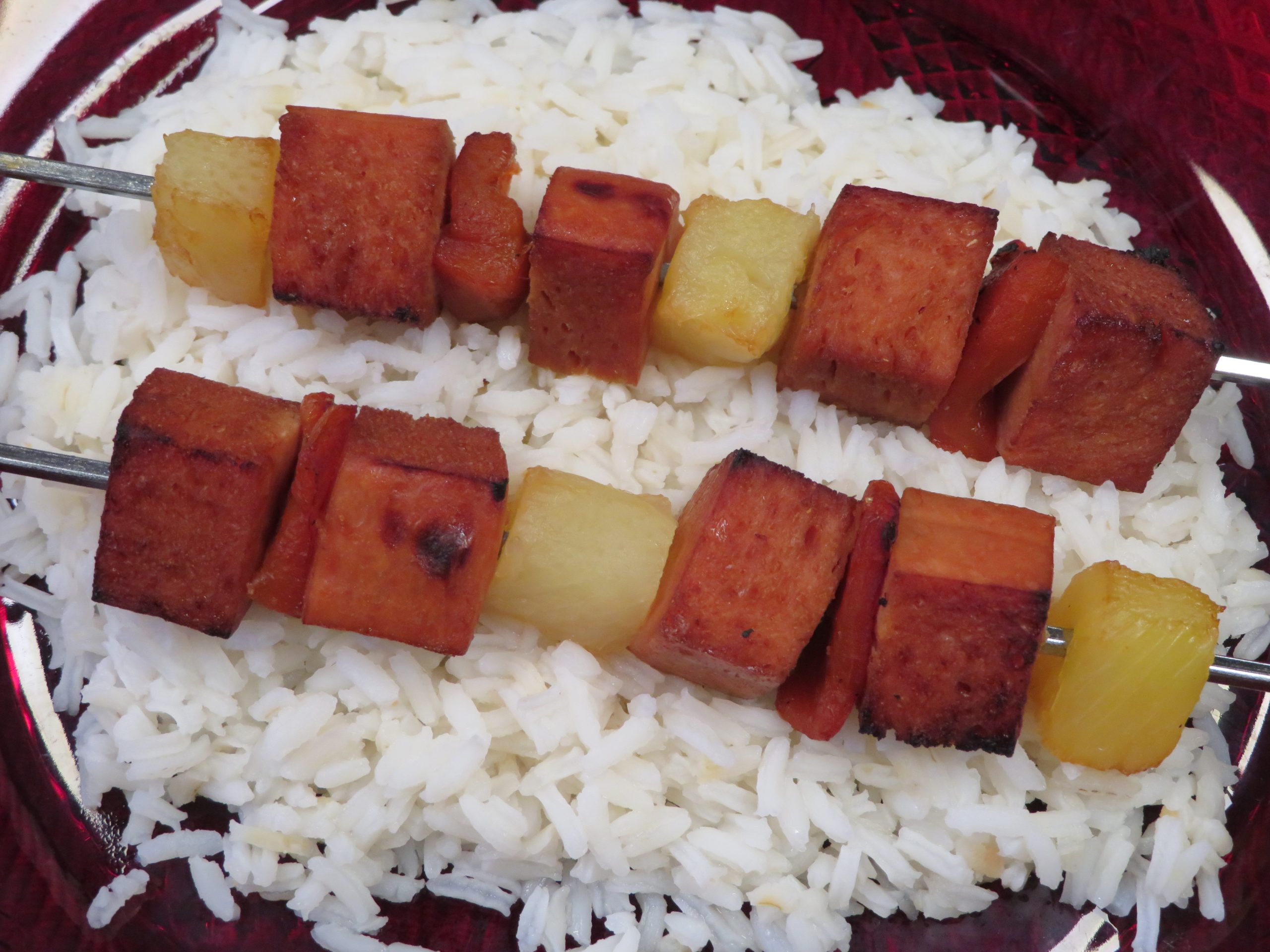 Two Turkey Kabob skewers laying on a bed of rice