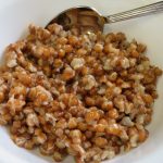 A bowl of cooked whole wheat with honey