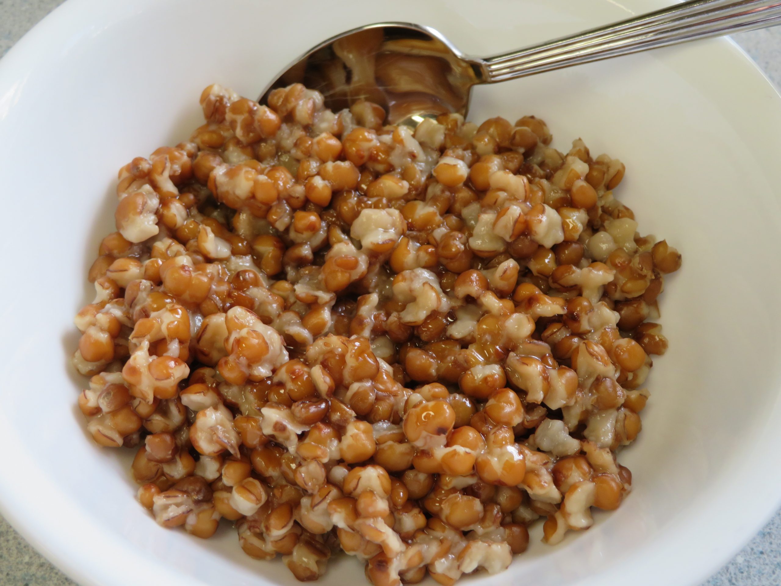 A bowl of cooked whole wheat with honey