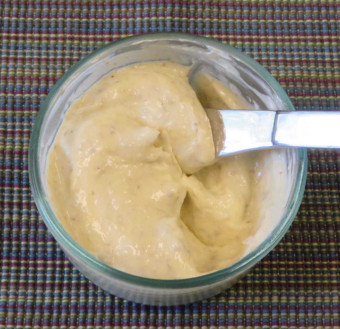 A bowl of pesto mayonnaise with a knife ready to spread