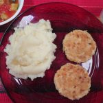 Dinner of chicken patties, mashed potatoes, tomatoes and zuchinni, and milk