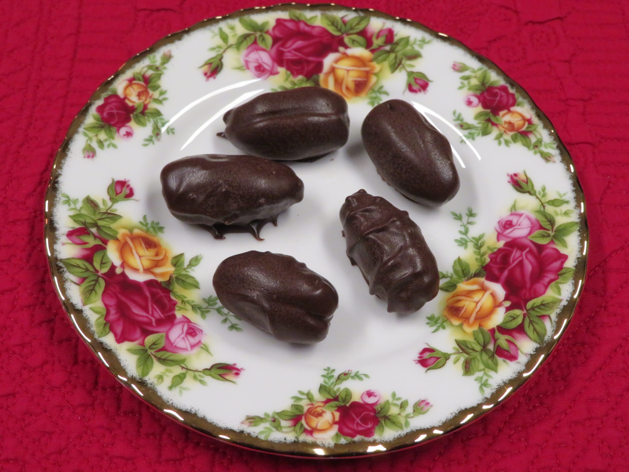 Chocolate covered pecans tuffed date sitting on a china plate