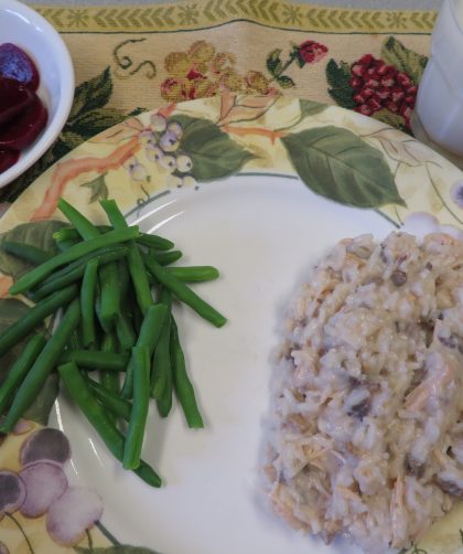 Creamy chicken and mushroom rice and green beans on a plate with pickled beets in a bowl and milk in a glass