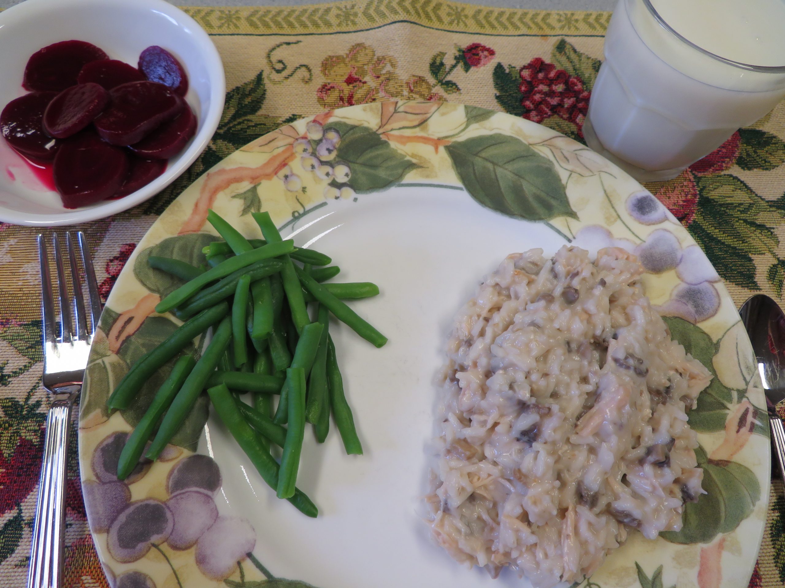 Creamy chicken and mushroom rice and green beans on a plate with pickled beets in a bowl and milk in a glass