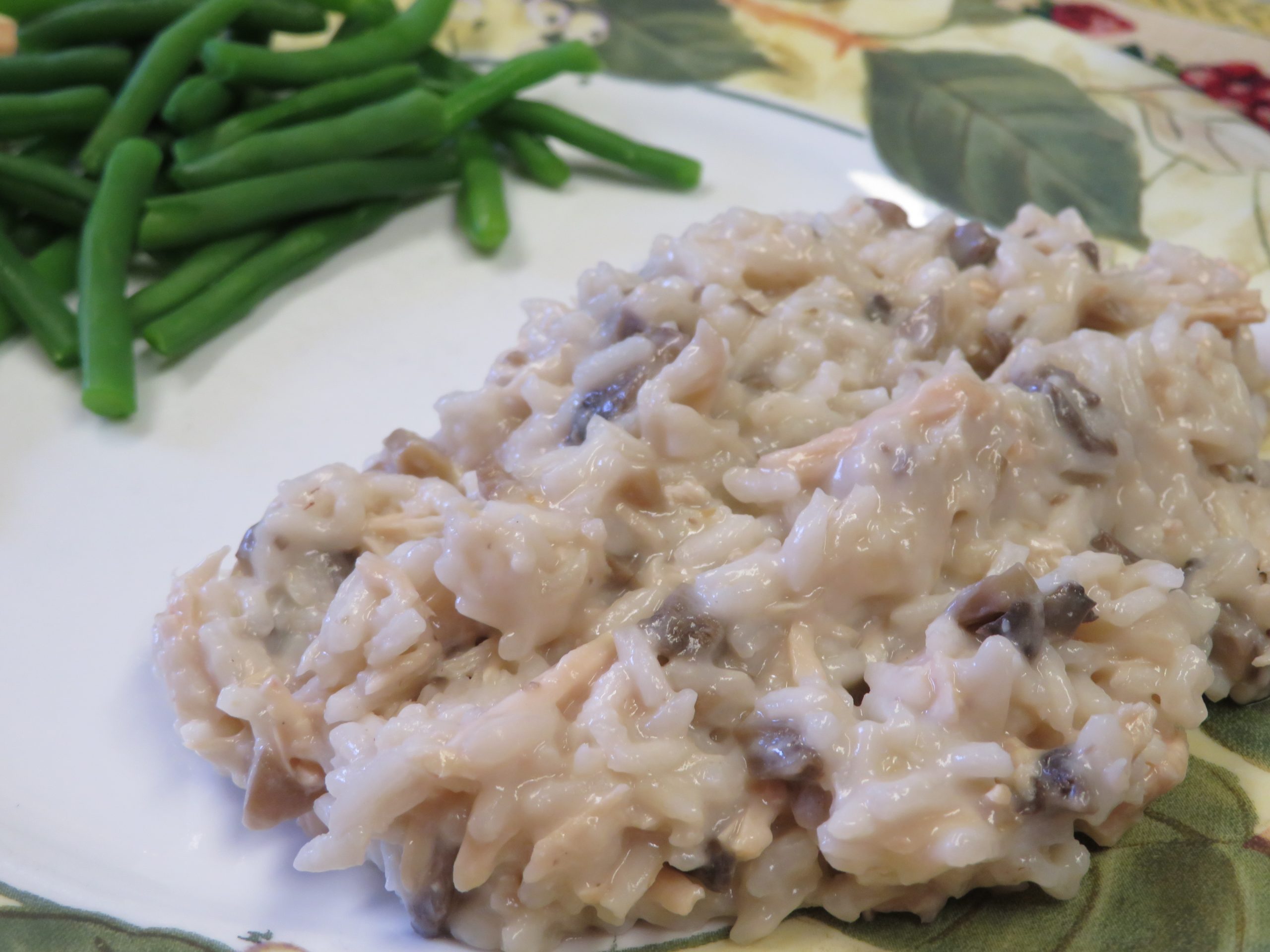 Creamy chicken and mushroom rice on a plate with fresh cooked green beans