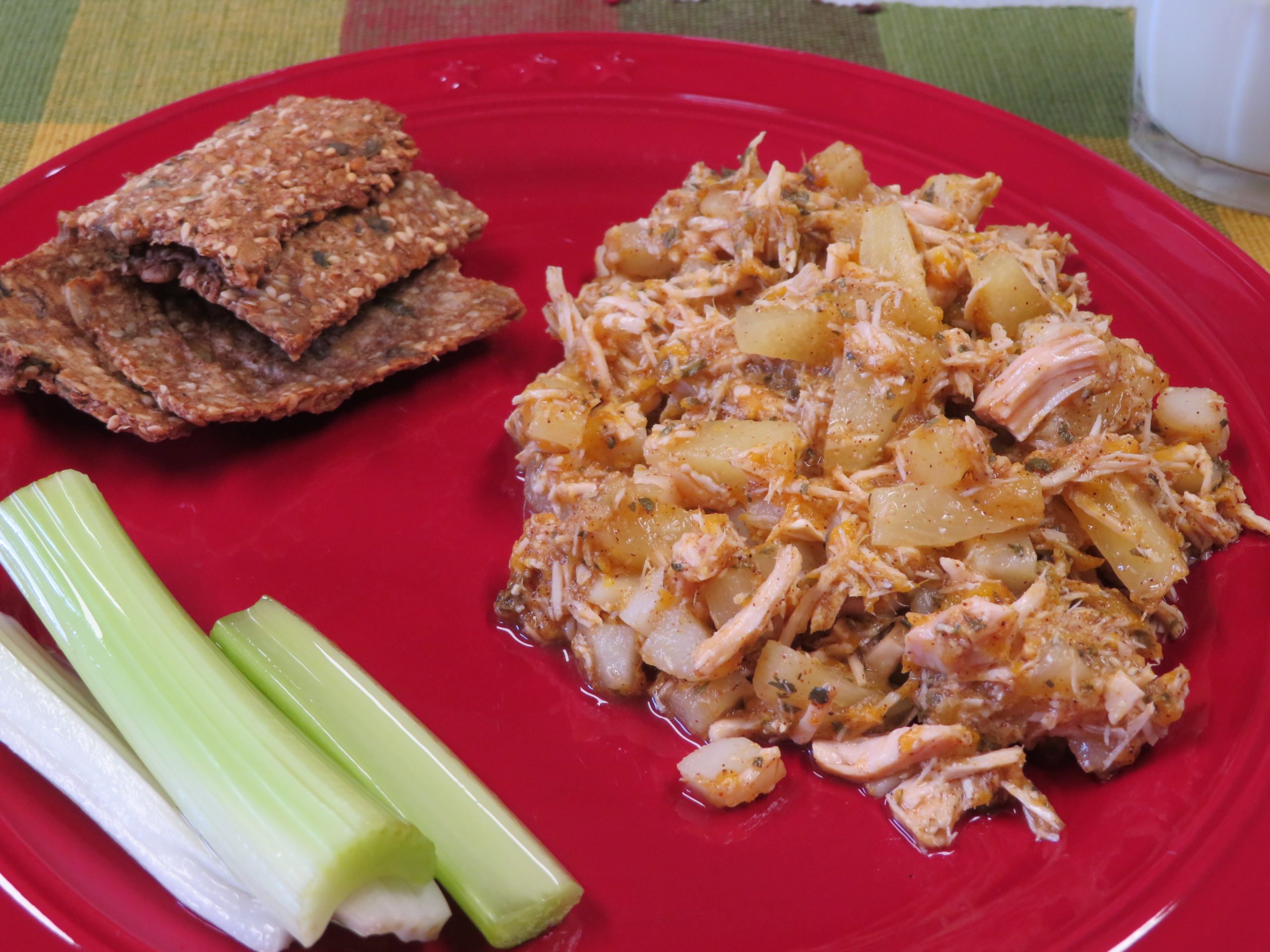 Tropical Pineapple Chicken Salad on a red plate with celery and crisp bread