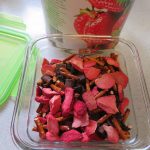 Strawberry snack mix beside the container lid and strawberry can