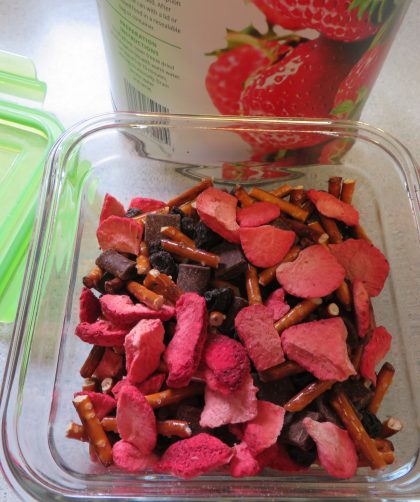 Strawberry snack mix beside the container lid and strawberry can