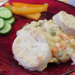 Chicken Pot Pie on a red plate with sliced cucumbers and orange bell pepper sticks