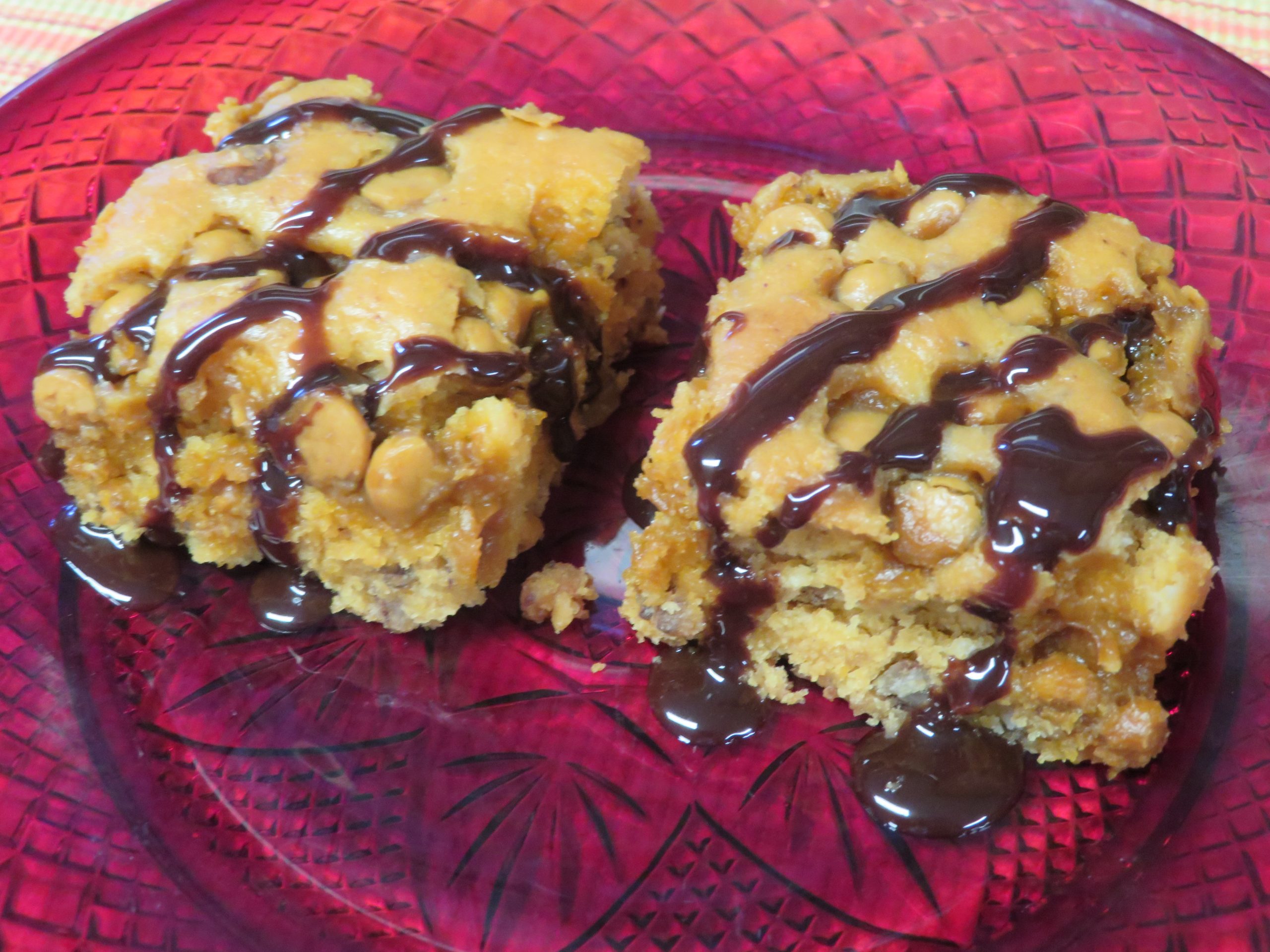 Butterscotch Bars drizzled with chocolate syrup on a red plate